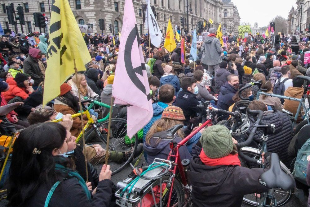 Protesters sitting in the road outside Parliament with flags and bicycles